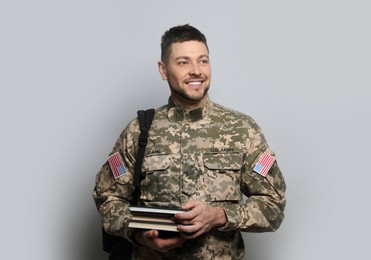 Cadet with backpack and books on light grey background. Military education