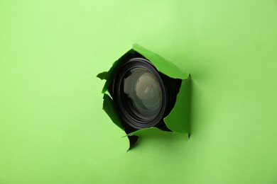 Hidden camera lens through torn hole in green paper