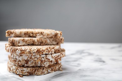 Stack of crunchy buckwheat cakes on white marble table, closeup. Space for text