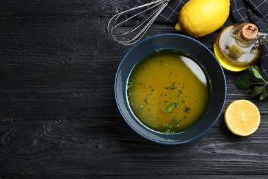 Photo of Bowl of lemon sauce and ingredients on black wooden table, flat lay with space for text. Delicious salad dressing