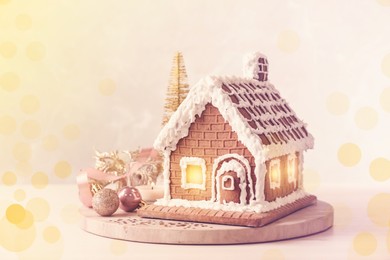 Beautiful gingerbread house decorated with icing and Christmas baubles on table