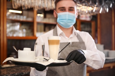 Waiter holding tray with beverages in restaurant. Catering during coronavirus quarantine