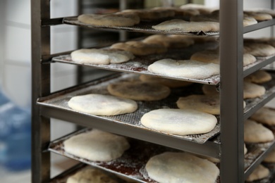 Rack with unbaked pastries in workshop, closeup