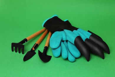 Gardening gloves and tools on green background
