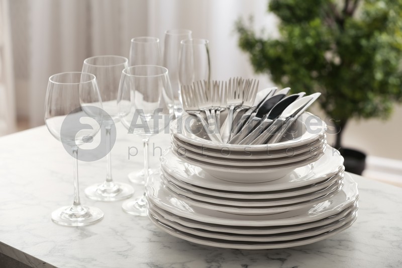 Photo of Set of clean dishware, cutlery and wineglasses on table indoors