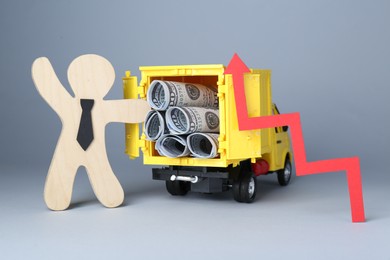 Economic profit. Wooden figure, arrow and toy truck with banknotes on light grey background
