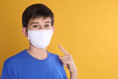 Boy wearing protective mask on yellow background, space for text. Child safety