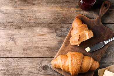 Tasty fresh croissants on wooden table, flat lay. Space for text