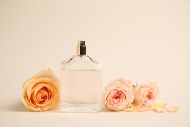 Bottle of perfume with roses on beige background