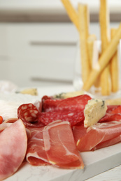 Tasty ham with other delicacies served on white wooden table, closeup