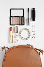 Photo of Stylish leather handbag and makeup items on white background, flat lay