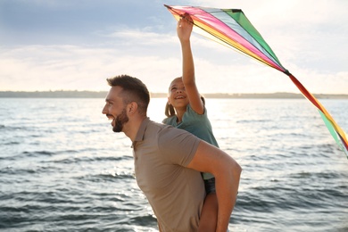 Happy father and his child playing with kite near sea. Spending time in nature
