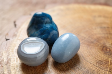Photo of Beautiful blue angelite, grey agate and shattuckite gemstones on wooden stand, closeup