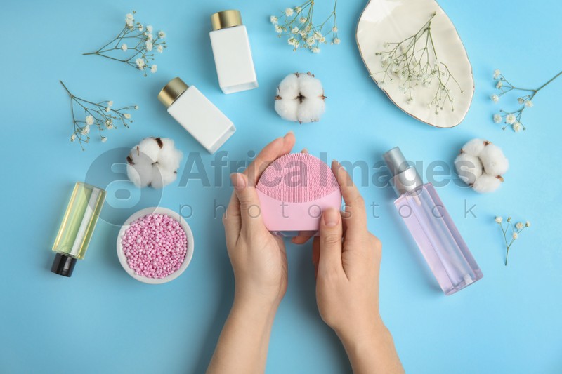Photo of Woman with face cleansing brush on light blue background, top view. Cosmetic accessory