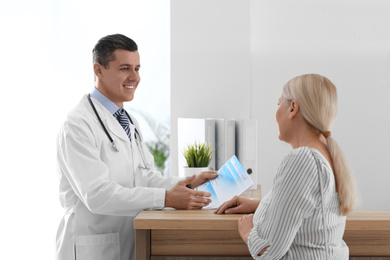 Doctor talking with patient near reception in hospital