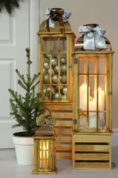 Beautiful Christmas lanterns and fir tree near entrance indoors