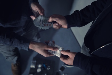 Addicted man buying drugs from dealer on blurred background, closeup