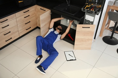 Male plumber repairing kitchen sink, above view