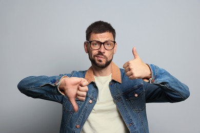 Man showing thumbs up and down on grey background