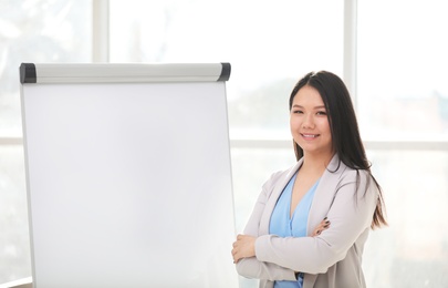 Photo of Business trainer standing near flip chart board indoors