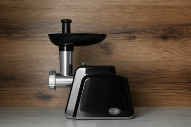 Photo of Modern electric meat grinder on light wooden table
