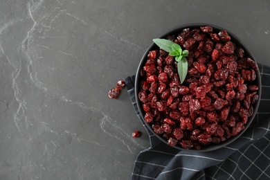 Photo of Bowl of dried cranberries on dark table, flat lay. Space for text