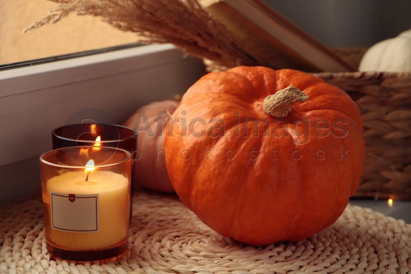 Scented candles and pumpkins on window sill indoors