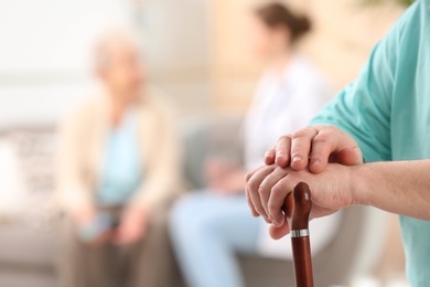 Closeup view of elderly man with cane in nursing home, space for text. Assisting senior generation