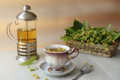 Aromatic tea with linden blossoms and spoon on white wooden table