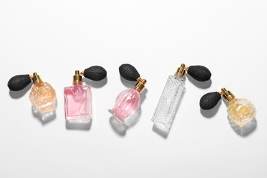 Different elegant perfume bottles on white background, top view