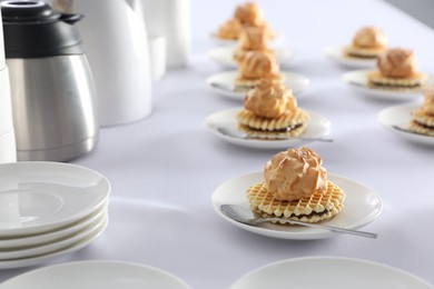 Photo of Many delicious waffles with cream served on white table for coffee break