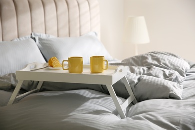 Soft blanket and tray with breakfast on bed indoors
