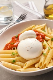 Delicious pasta with burrata cheese and sauce on light grey table, closeup
