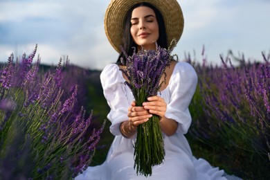 Beautiful young woman with bouquet in lavender field