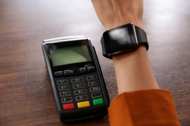 Woman making payment with smart watch at table, closeup