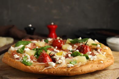 Pita pizza with prosciutto, pineapple, grilled tomatoes and egg on wooden table, closeup