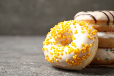 Photo of Delicious glazed donuts on grey table, closeup. Space for text