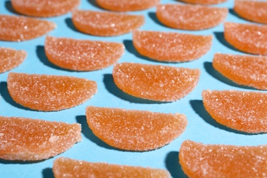 Delicious orange marmalade candies on light blue background