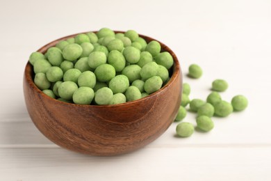 Bowl with tasty wasabi coated peanuts on white wooden table, closeup. Space for text