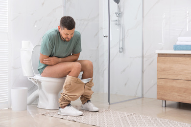 Man suffering from hemorrhoid on toilet bowl in rest room