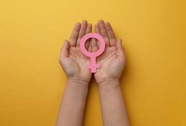 Woman holding female gender sign on orange background, top view
