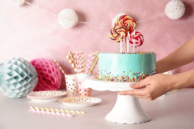 Woman putting stand with fresh delicious cake on against color background, closeup. Space for text