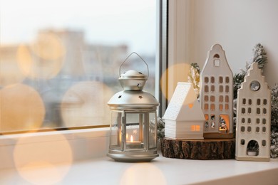 Photo of Beautiful house shaped candle holders and Christmas decor on windowsill indoors, space for text. Bokeh effect