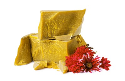 Photo of Natural organic beeswax blocks and flowers on white background