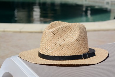 Stylish hat near outdoor swimming pool on sunny day. Beach accessory