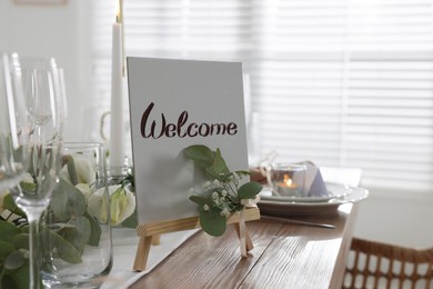 Festive table setting with floral decor and Welcome sign indoors