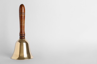 Golden school bell with wooden handle on grey background. Space for text