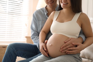 Man touching his pregnant wife's belly at home, closeup