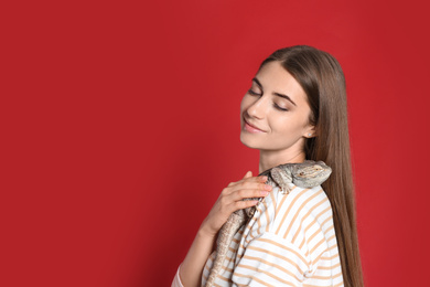 Woman holding bearded lizard on red background. Exotic pet
