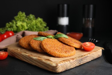 Photo of Delicious fried breaded cutlets served on black table
